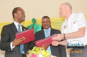 The Lusaka City Mayor Mulenga Sata exchanging documents with the ZANACO MD Dick Bruce while looking on is Deputy Minister of Local Government and Housing Nicolas Banda during launch between Zanaco and Lusaka City Council Direct Debit and Credit Clearing (DDACC) at the Nkatindi Hall