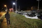 A pedestrian passes by damaged cars in a used car dealership Tuesday, Nov. 25, 2014, in Dellwood, Mo.